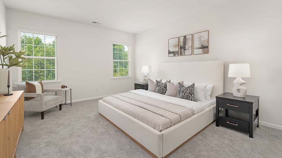 Carpeted primary bedroom with two small windows