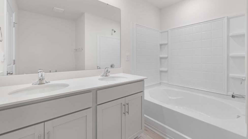Bathroom with white cabinets and counters, and bathtub