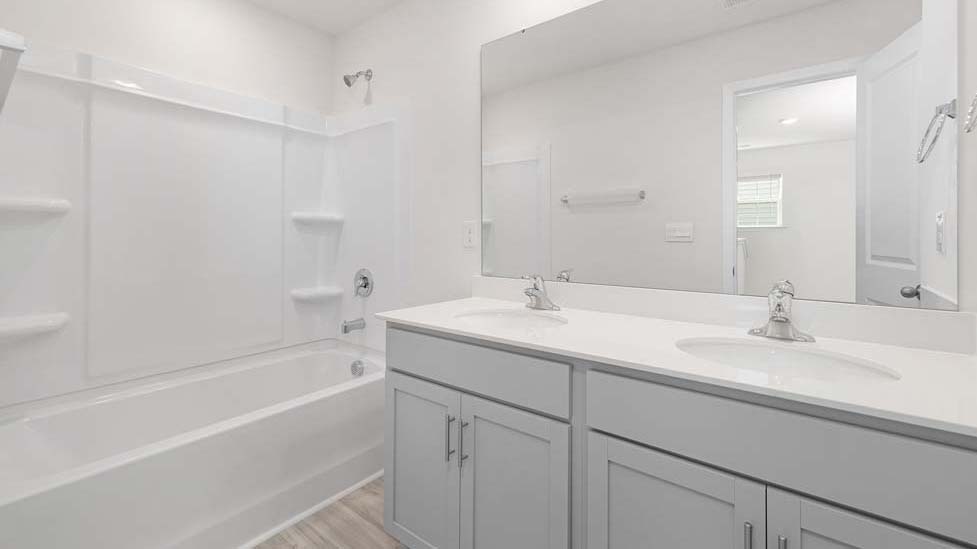 Bathroom with white cabinets and counters, and bathtub