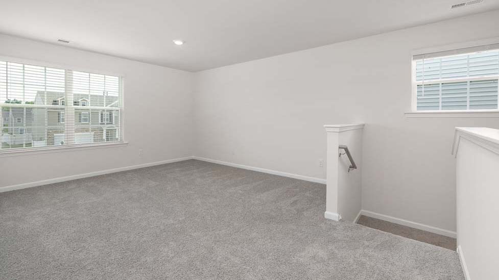 Carpeted loft space atop stairs with large window