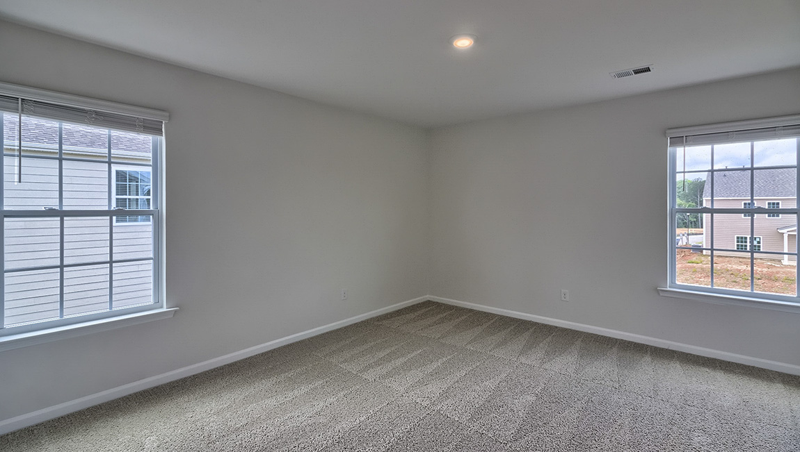Carpeted bedroom with two large windows