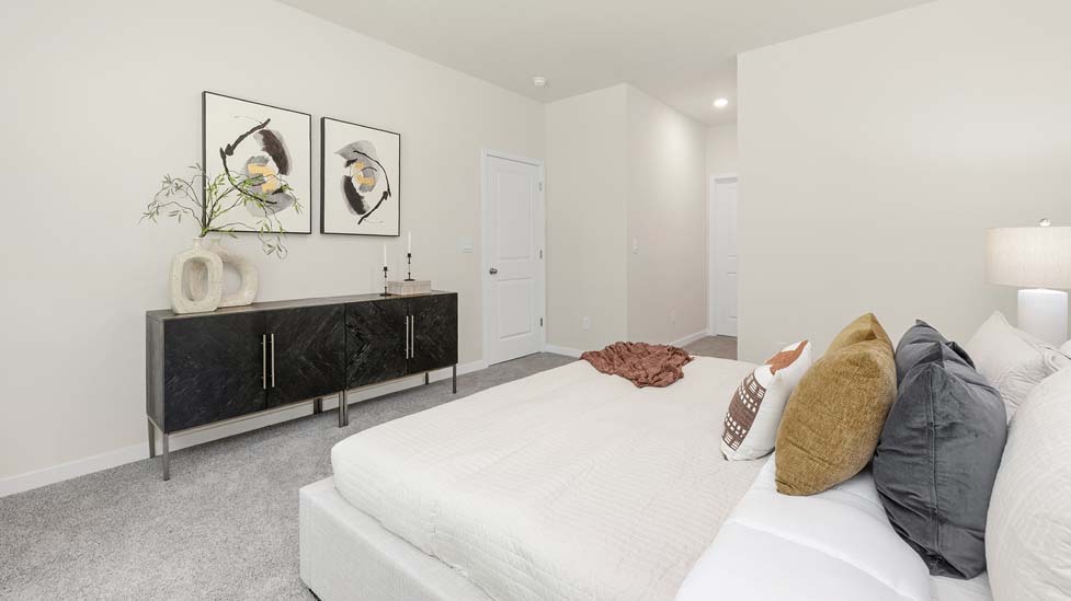 Carpeted primary bedroom with large window and ceiling fan. New Home in Charlotte, North Carolina