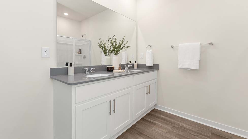 Primary Bathroom with white cabinets and counters, double vanity, and glass door shower. New Home in Charlotte, North Carolina