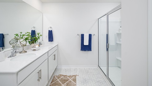 Bathroom with white cabinets and counters, double vanity, and glass door shower. New Home in Charlotte, North Carolina