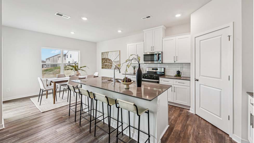 Kitchen and island with white cabinets, quartz counters, wood floors and stainless steel appliances