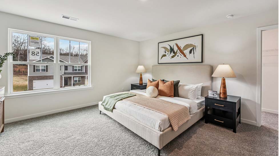 Primary carpeted bedroom with windows