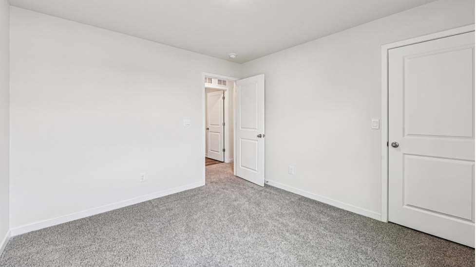 Carpeted bedroom with large window, view of bathroom door