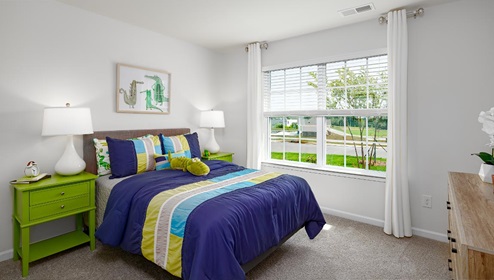 Carpeted bedroom with large window. New Home in Charlotte, North Carolina