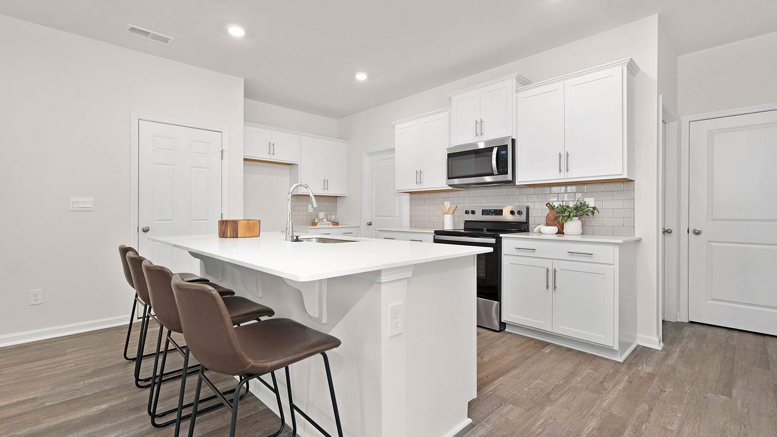 Kitchen and island with white cabinets and wood flooring