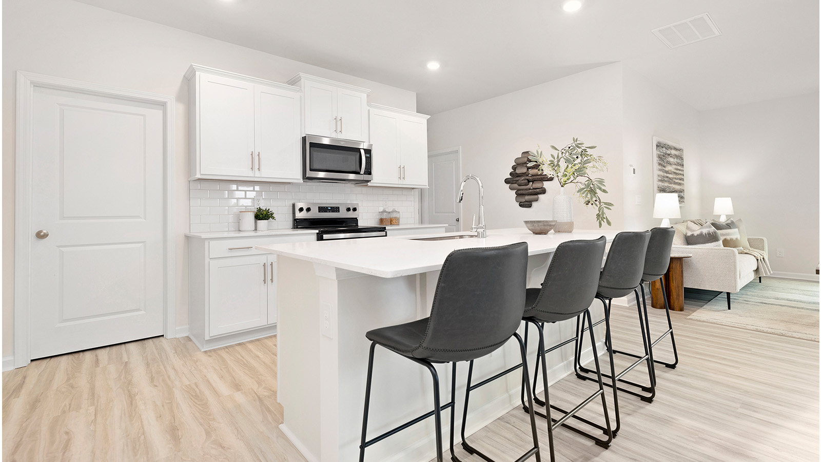 Kitchen and island with white cabinets, counters, subway tile backsplash and stainless steel appliances