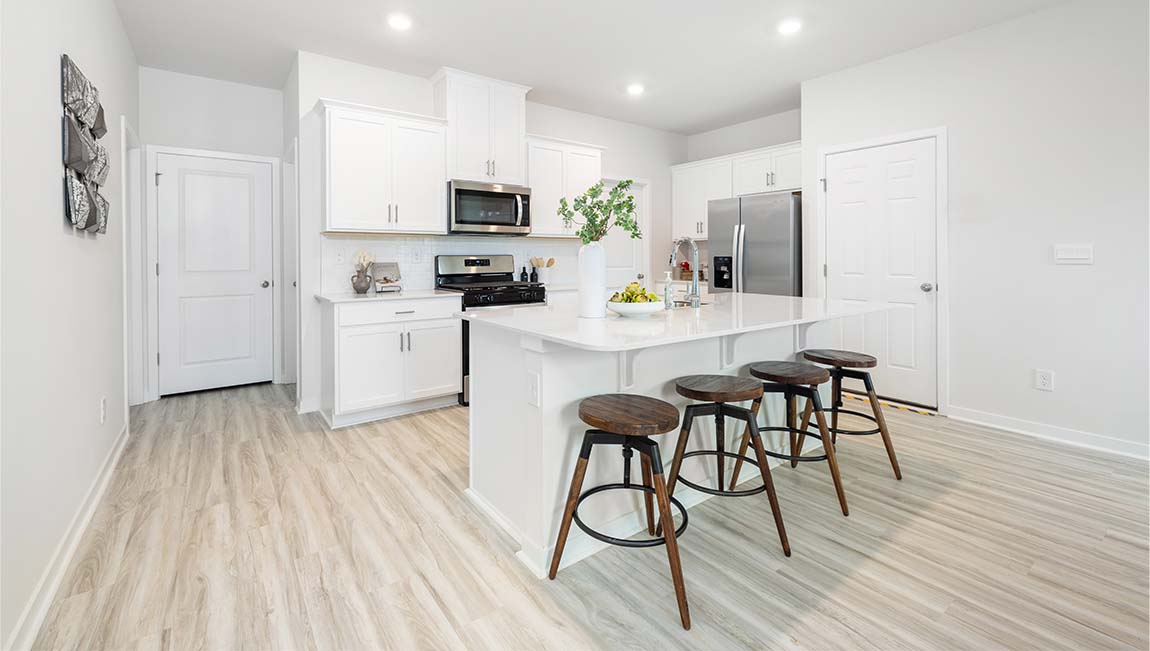 Kitchen and island with white cabinets and wood flooring