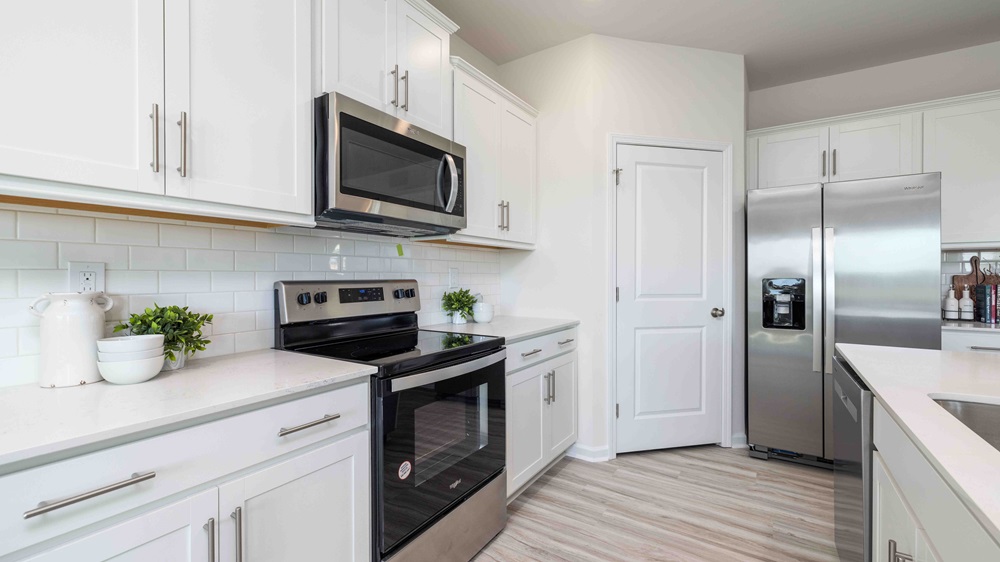Kitchen and island with white cabinets, quartz counters, wood floors and stainless steel appliances