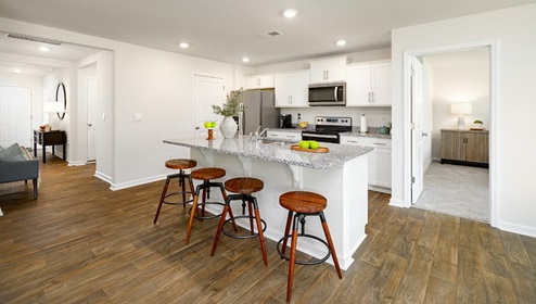 Kitchen and island with white cabinets, breakfast area at island, and stainless steel appliances. New Home in Charlotte, North Carolina
