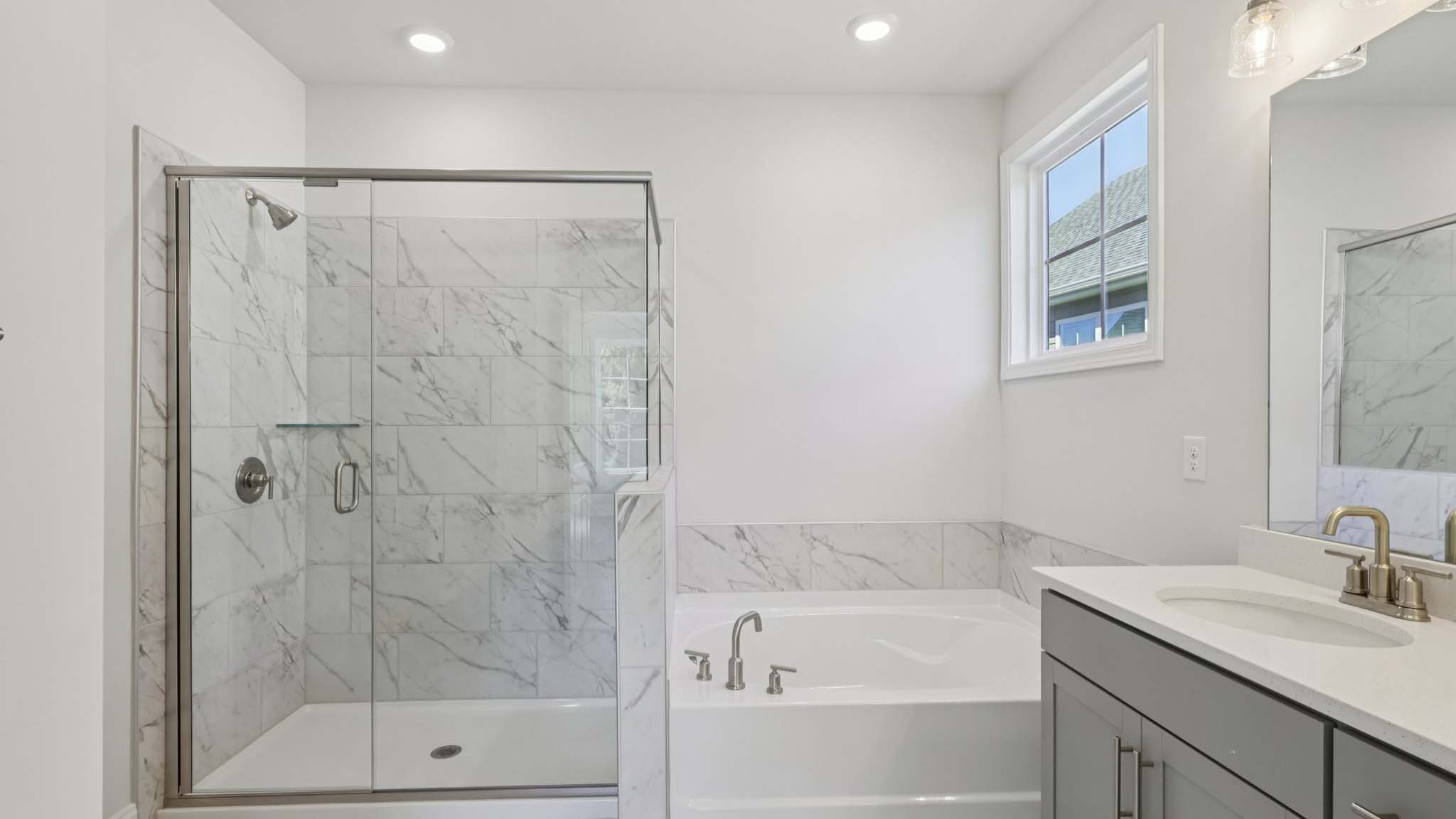 primary bathroom with double sink vanity and large glass shower and bathtub