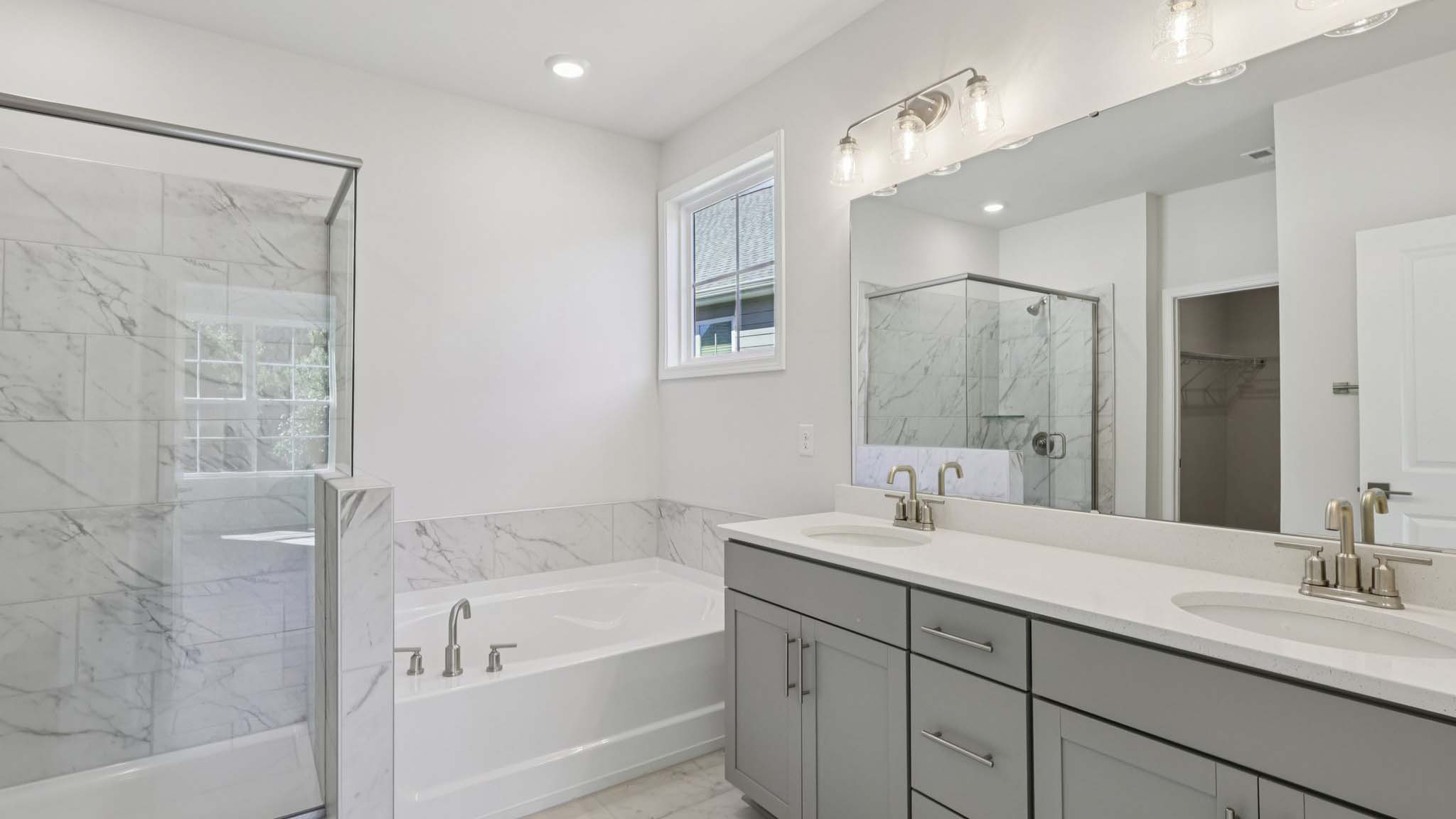 primary bathroom with double sink vanity and large glass shower and bathtub