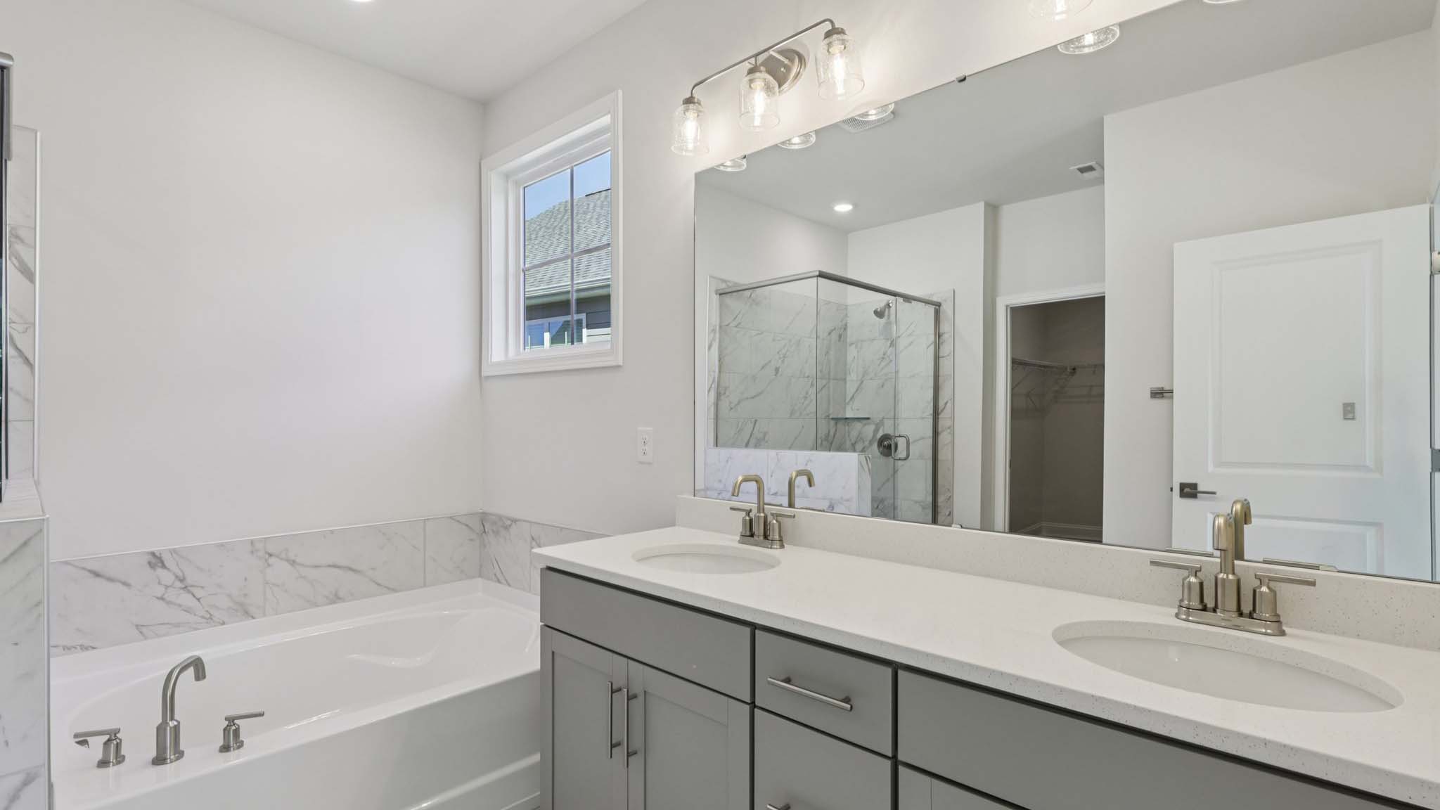 primary bathroom with double sink vanity and large glass shower and bathtub