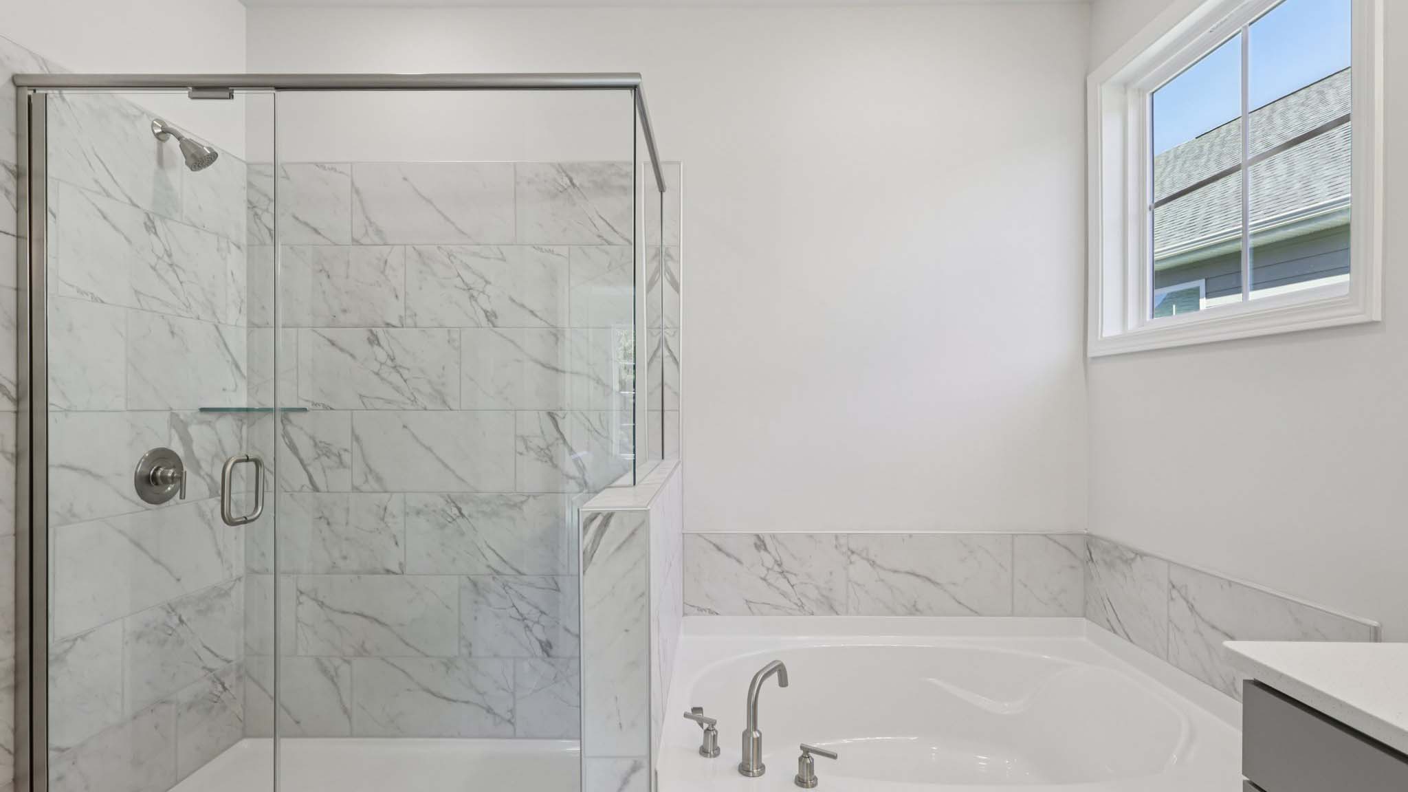 primary bathroom with double sink vanity and large glass shower and bathtub