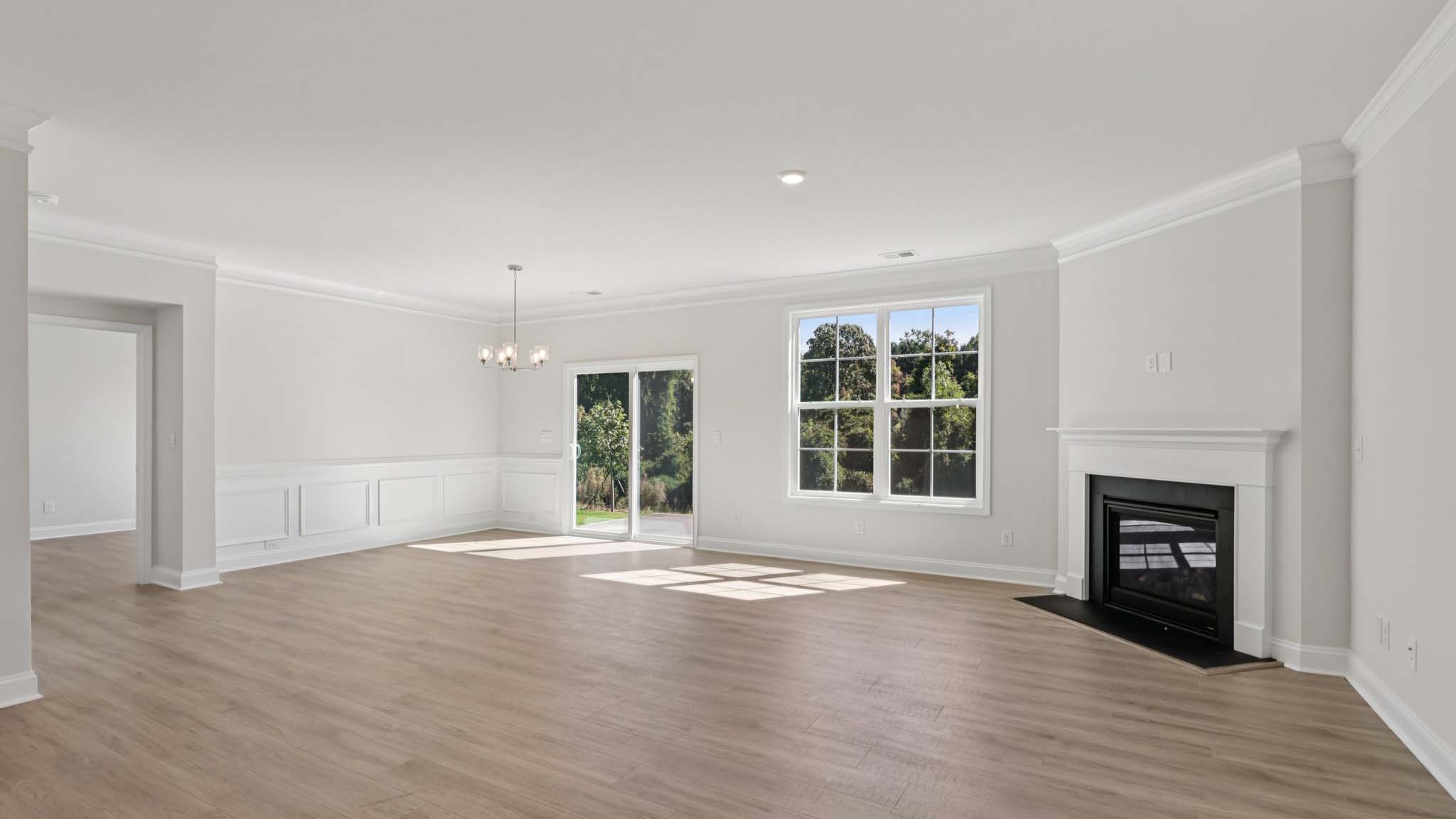 living room beside kitchen with large windows and fireplace