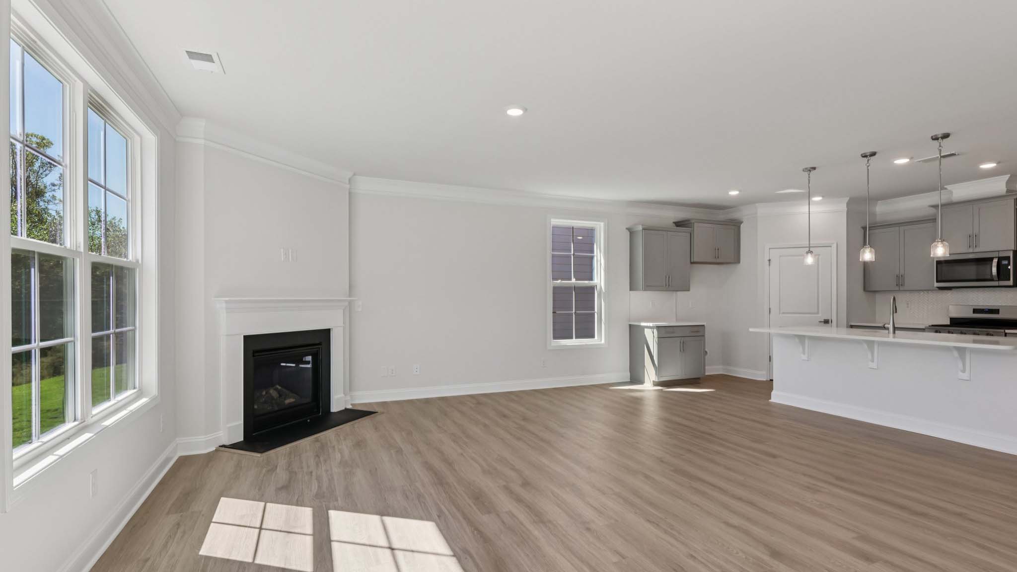 living room beside kitchen with large windows and fireplace