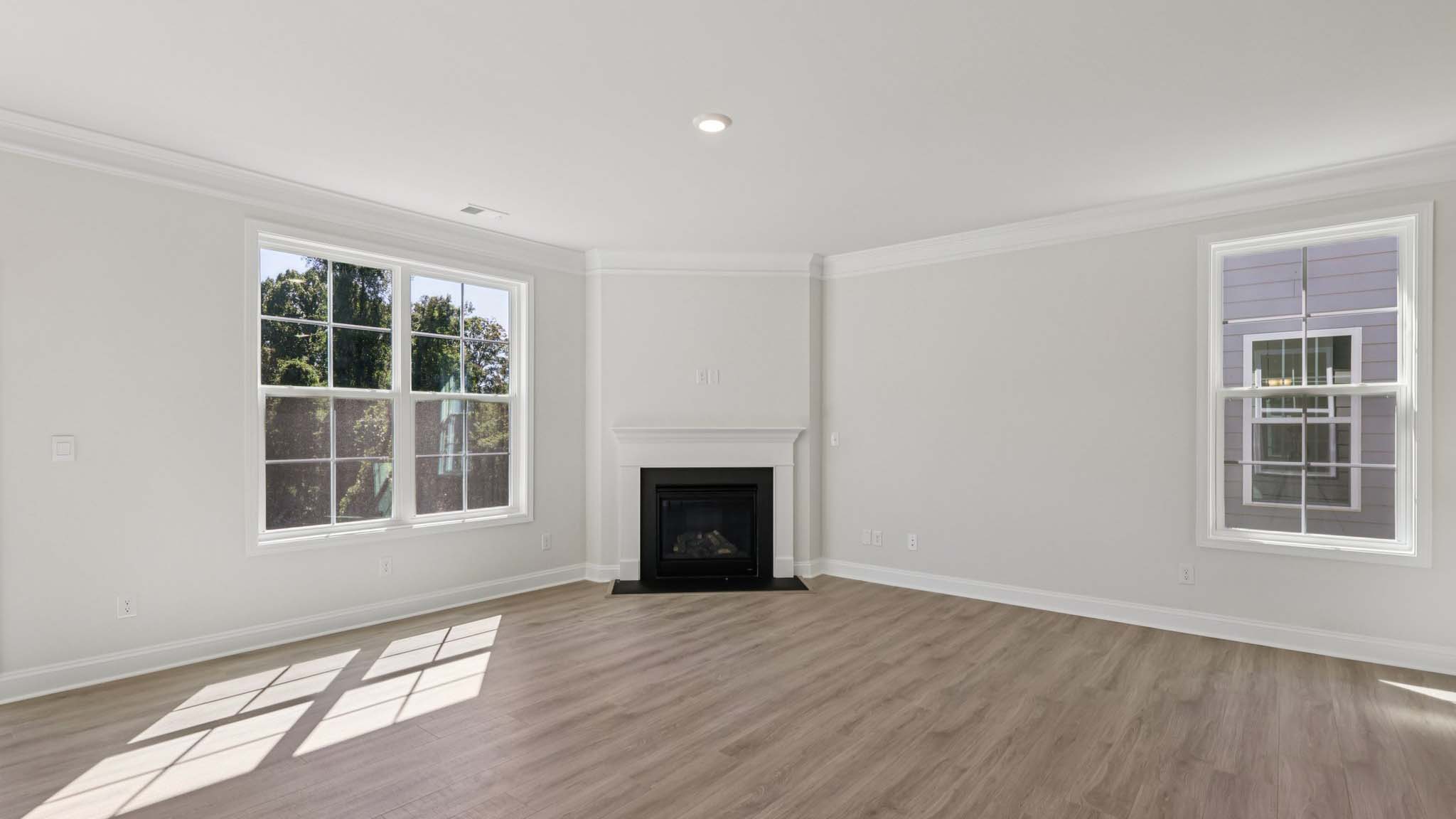 living room beside kitchen with large windows and fireplace