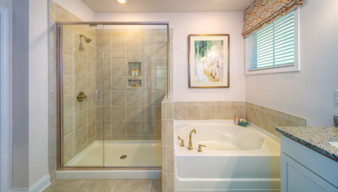 Primary bathroom with white cabinets, and bathtub and glass door shower combination