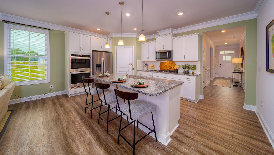 Kitchen and island with wood floors, white cabinets, and stainless steel appliances