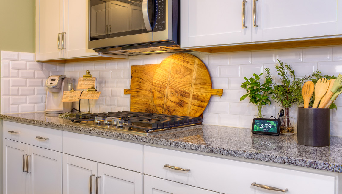 Kitchen and island with wood floors, white cabinets, and stainless steel appliances