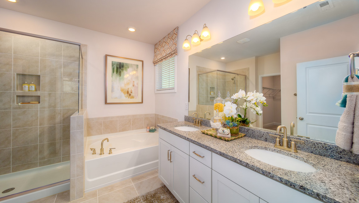 Primary bathroom with white cabinets, and bathtub and glass door shower combination