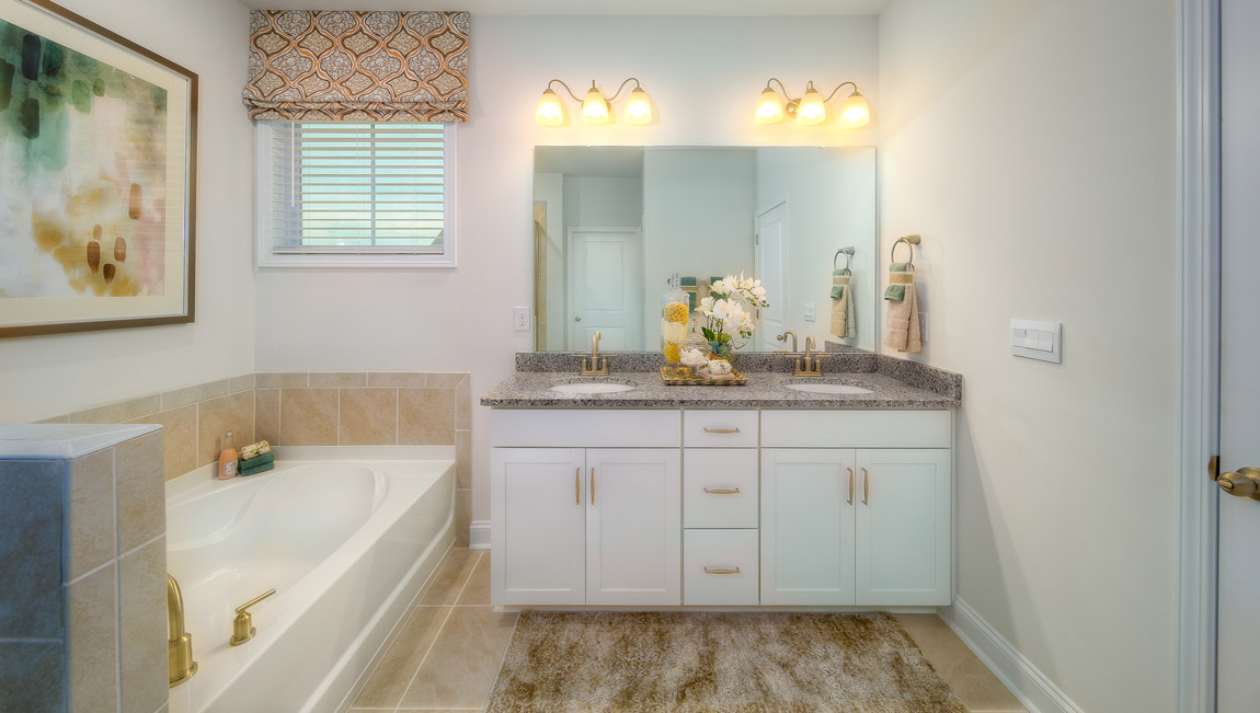 Primary bathroom with white cabinets, and bathtub and glass door shower combination