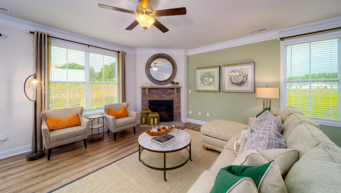 Open living room with wood floors, fireplace, and two large windows