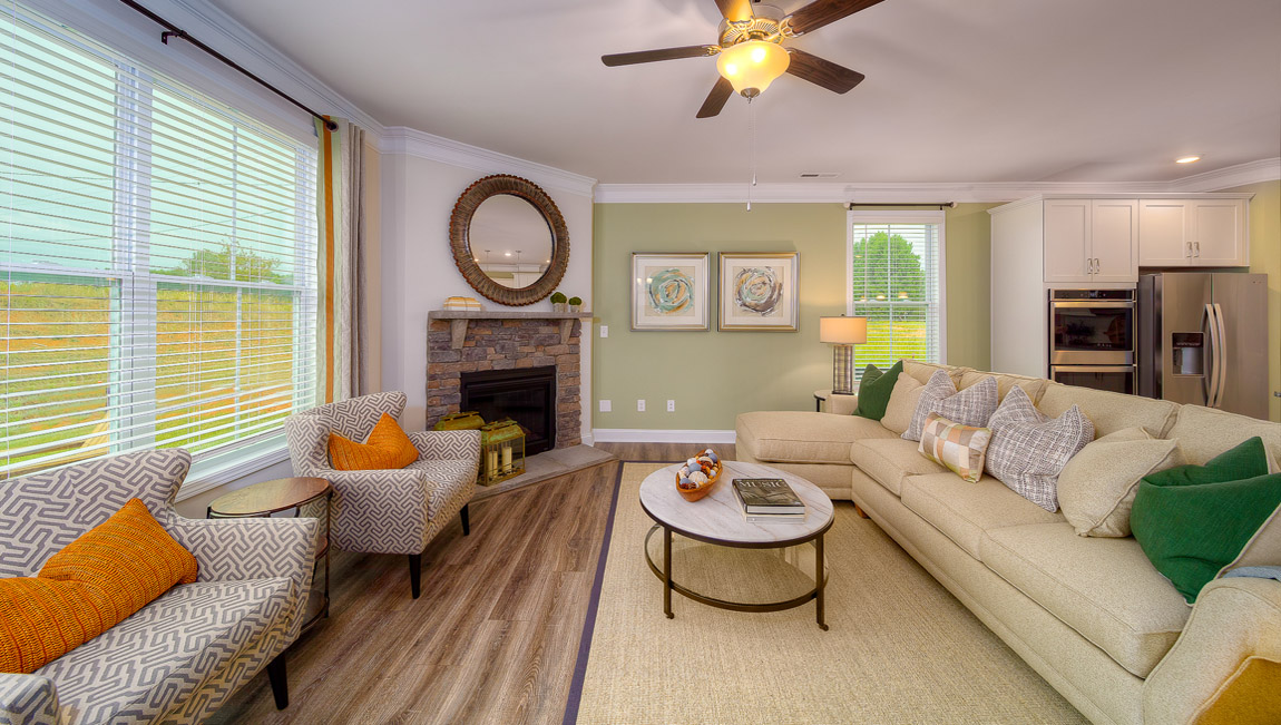 Open living room with wood floors, fireplace, and two large windows