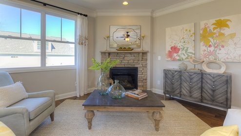Open family room in view of dining room, with wood floors, large window and fireplace