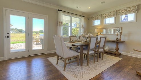 Dining room with wood floors, large windows, and back door to patio