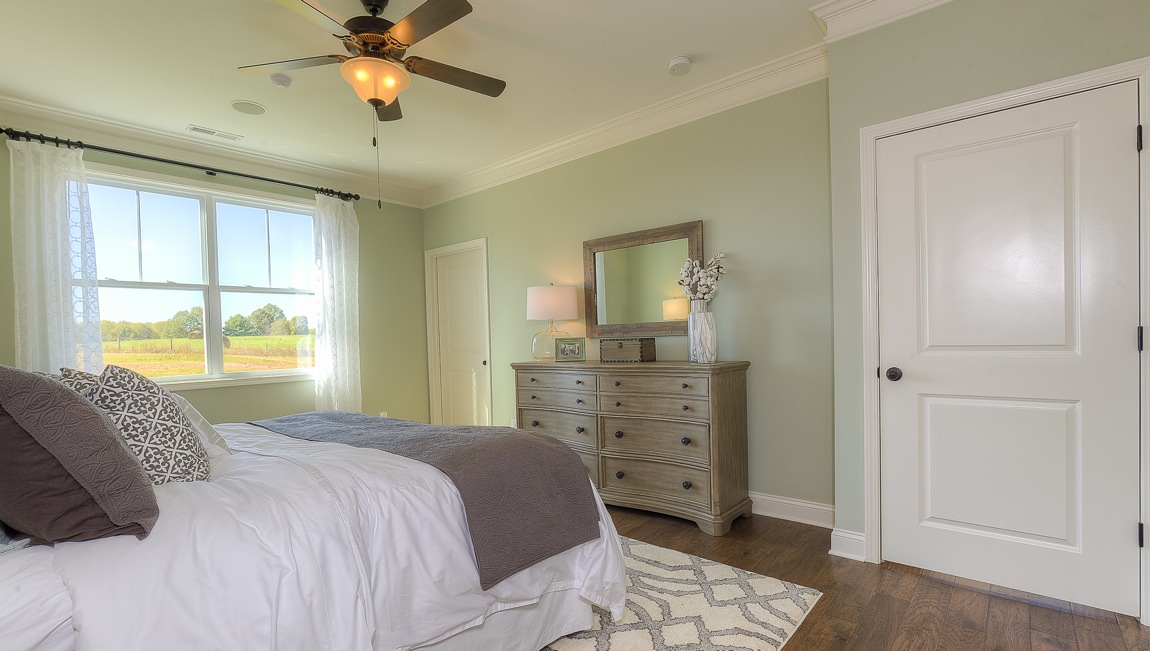 Primary bedroom with wood floors, and large window