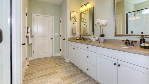 Primary bathroom with double sinks, and white cabinets