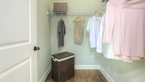 Primary bedroom storage closet with racks for hanging and wood floors