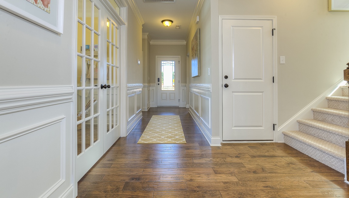 Welcoming foyer with wood floors, view of french doors, front door and staircase