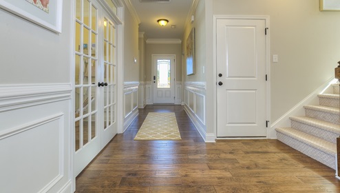 Welcoming foyer with wood floors, view of french doors, front door and staircase