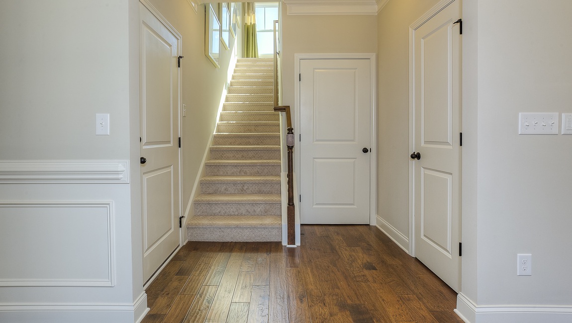 Entrance to primary bedroom with stair and wood floors