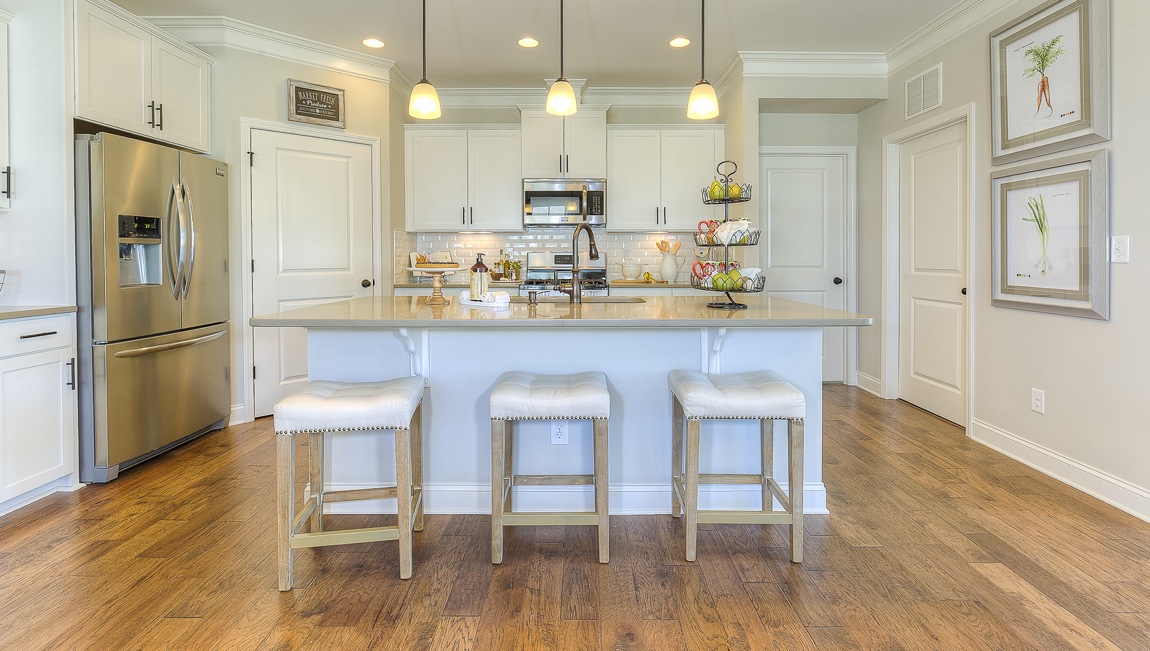 Kitchen and island with wood floors, white cabinets, breakfast area at island bar, and stainless steel appliances