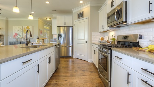 Kitchen and island with wood floors, white cabinets, breakfast area at island bar, and stainless steel appliances