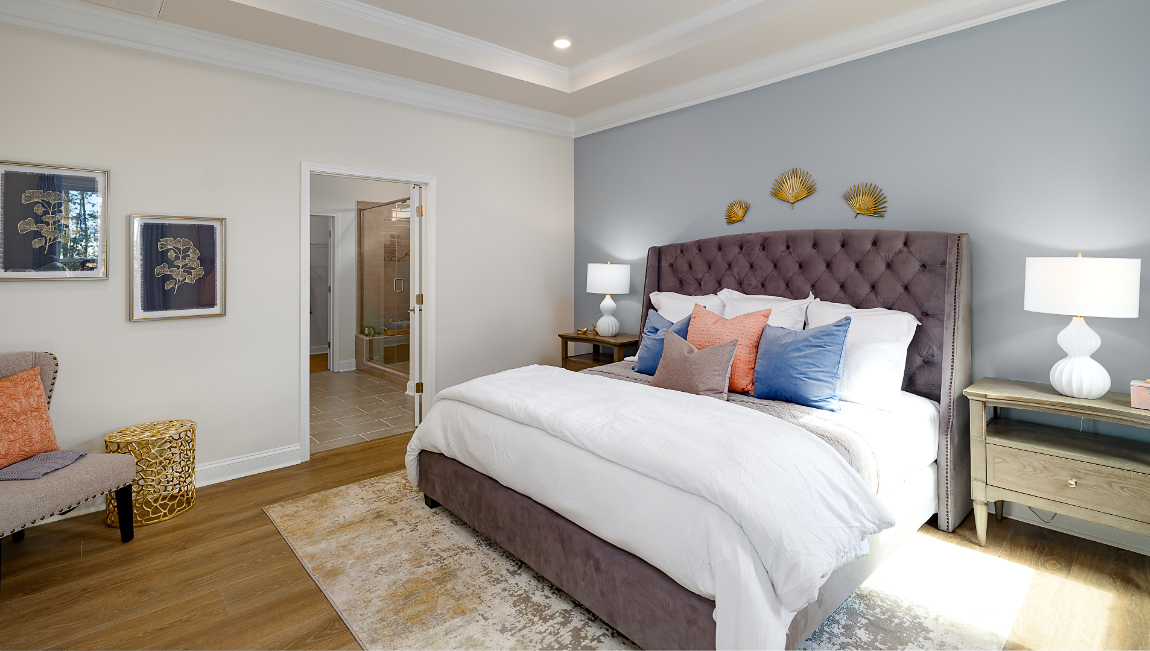 Primary bedroom with wood floors, and two large windows