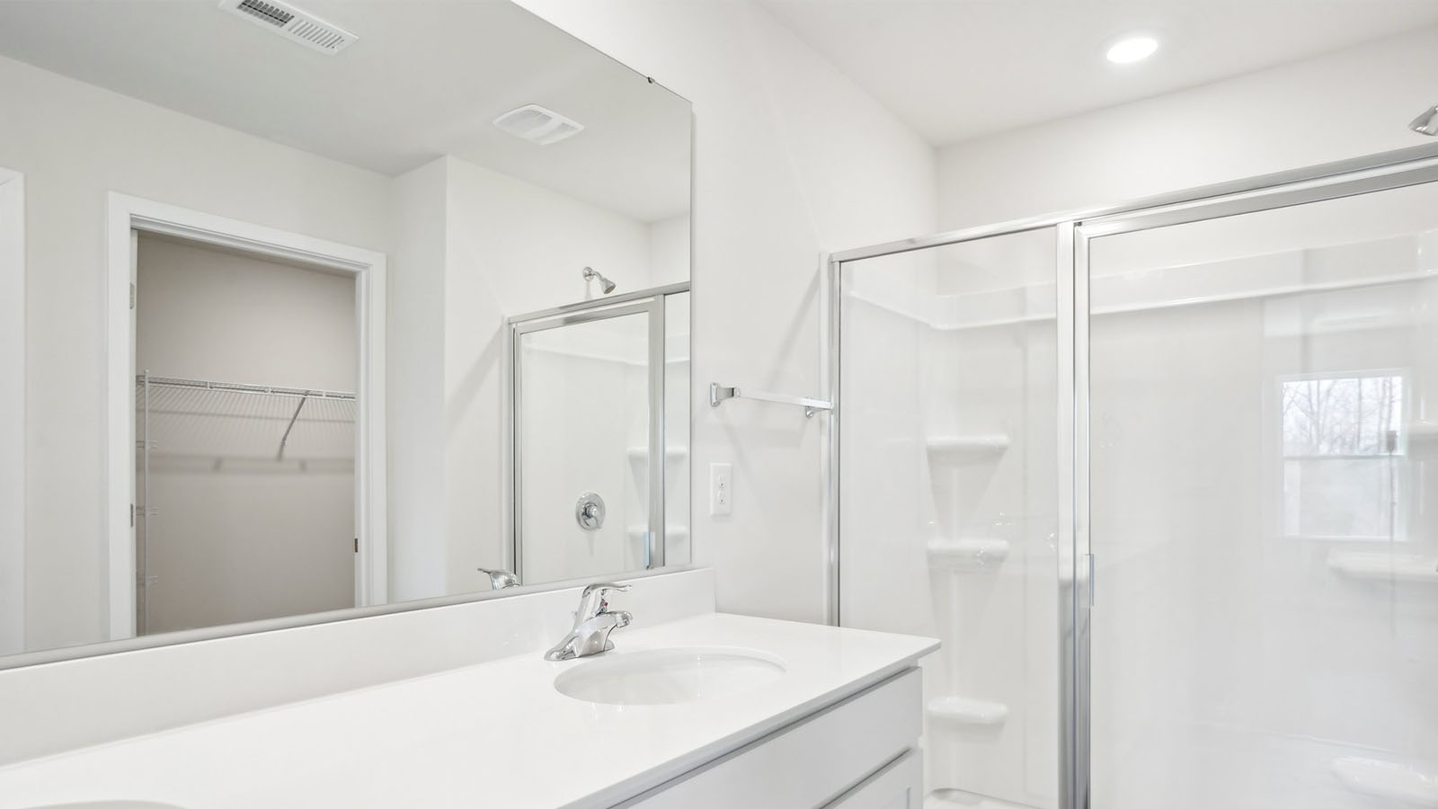 Bathroom with double sink vanity, standing glass door shower and connected walk in closet