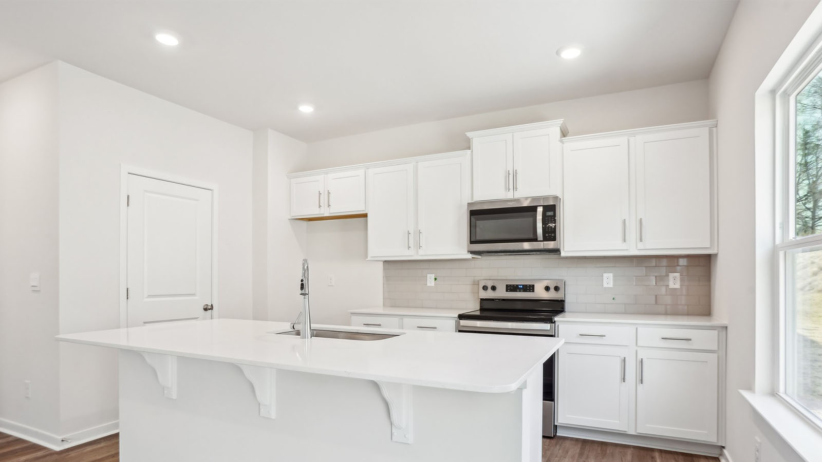 Kitchen and island with subway tile backsplash and stainless steel appliances