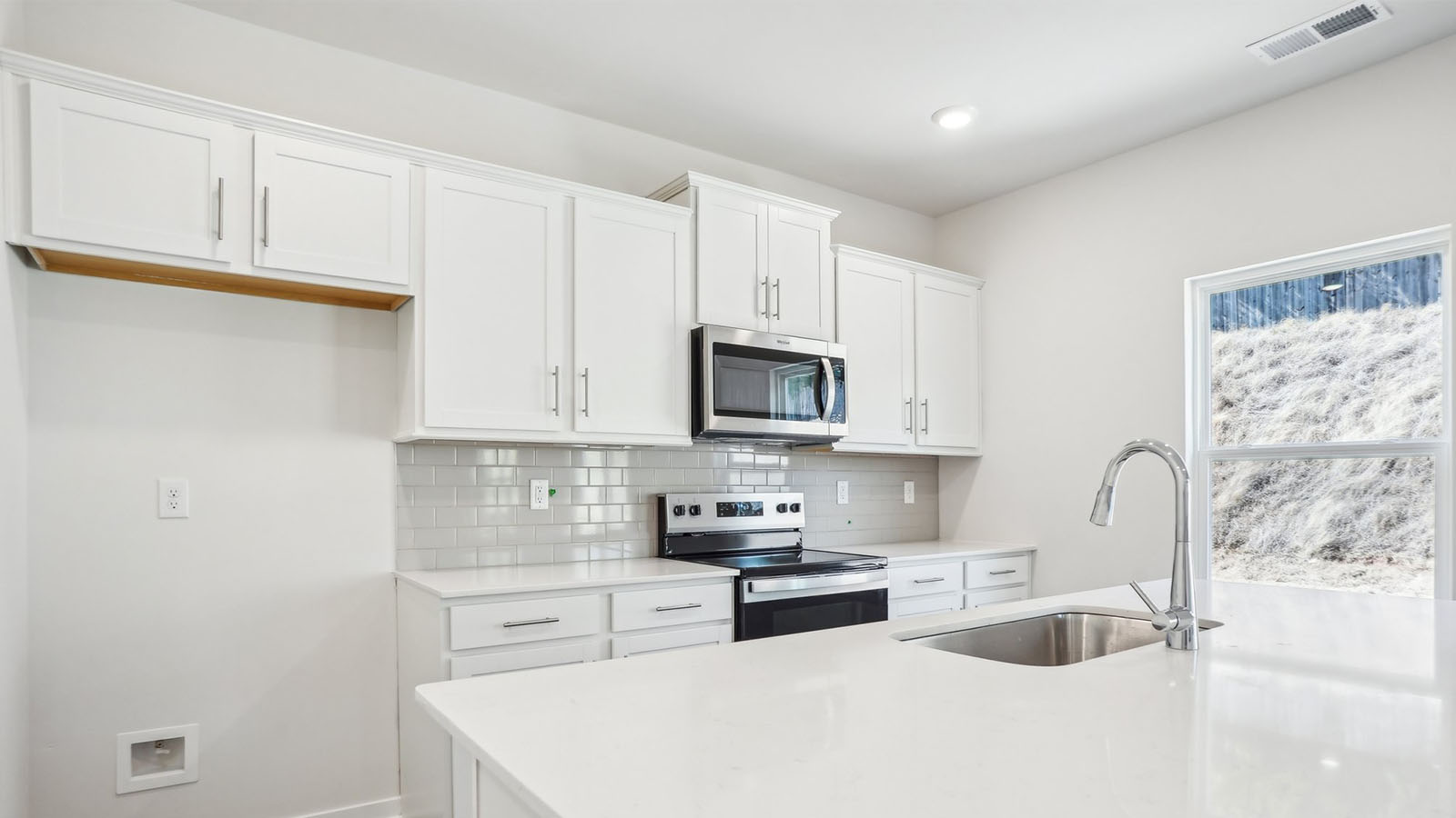 Kitchen and island with subway tile backsplash and stainless steel appliances