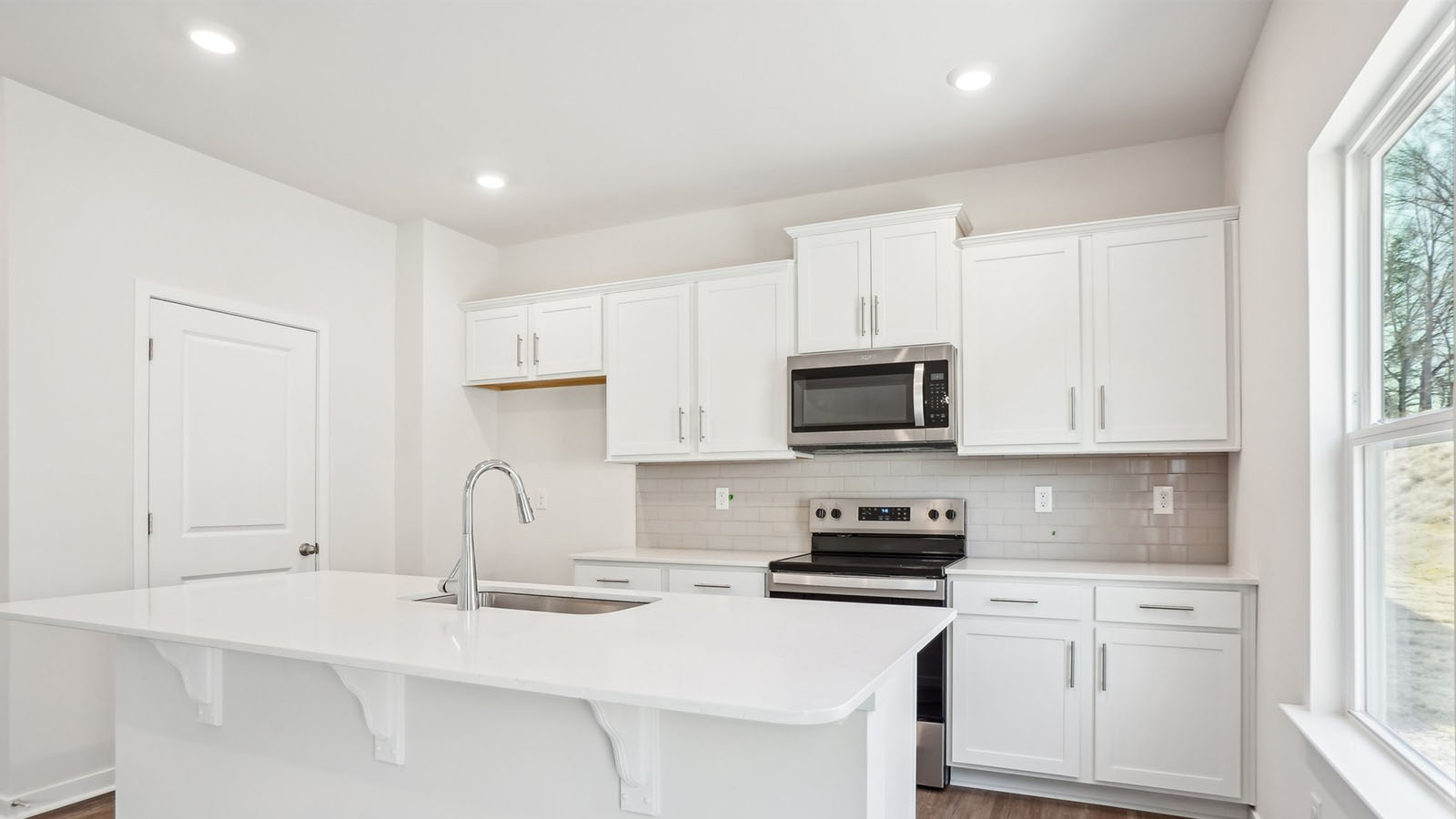 Kitchen and island with subway tile backsplash and stainless steel appliances