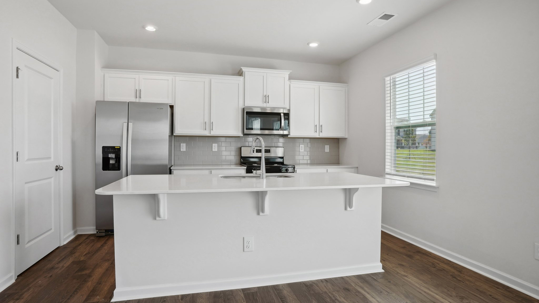 Kitchen and island with subway tile backsplash and stainless steel appliances