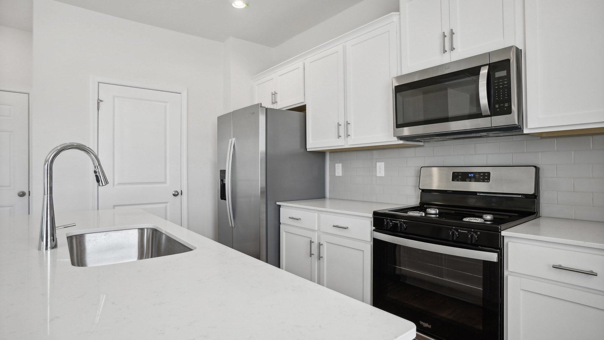 Kitchen and island with subway tile backsplash and stainless steel appliances