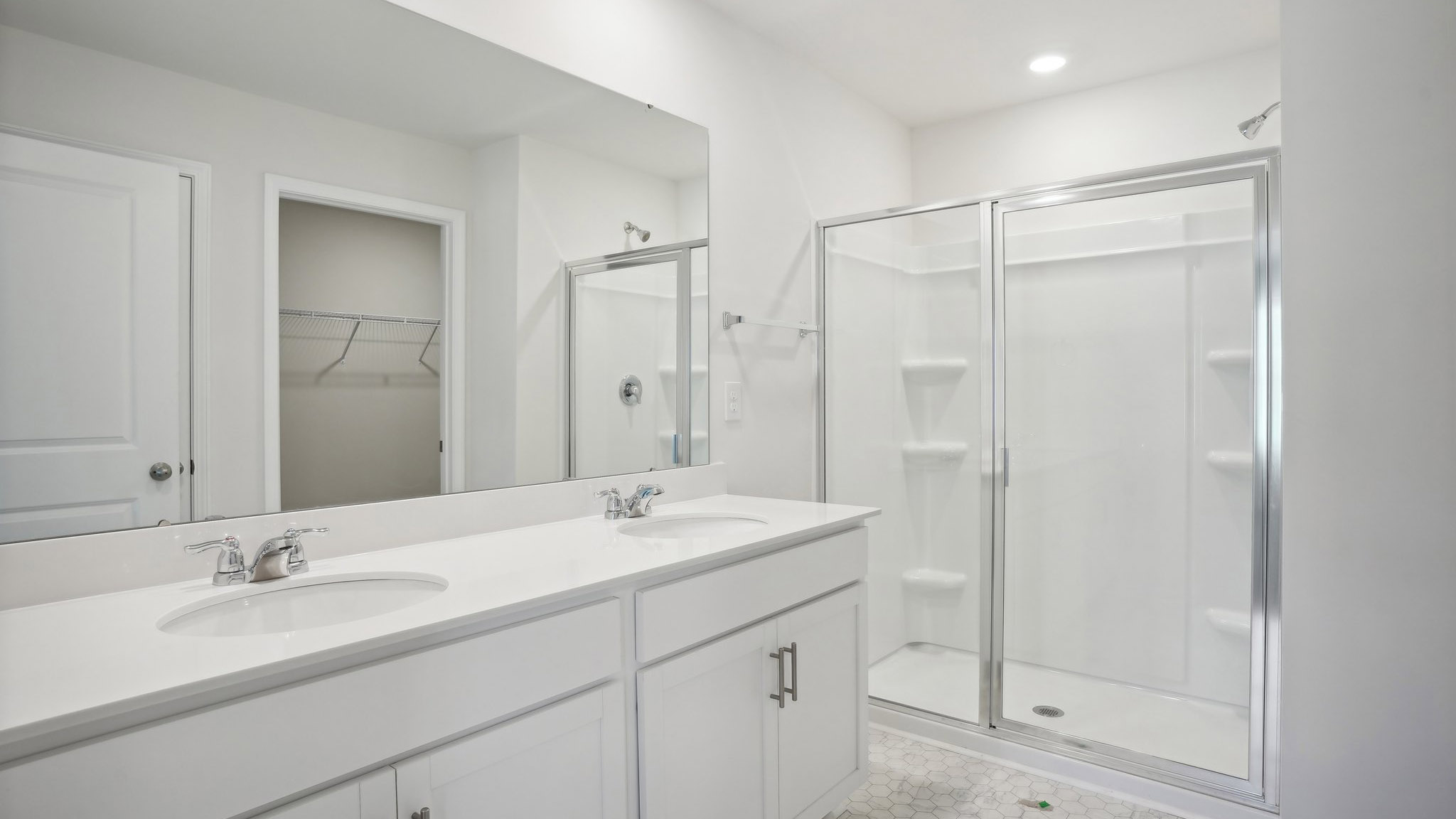 Bathroom with double sink vanity, standing glass door shower and connected walk in closet