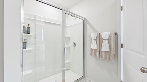 Primary bathroom with double vanity and glass door shower
